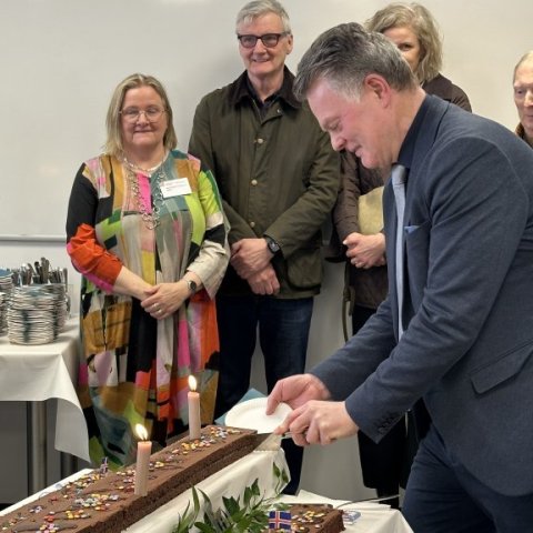 Halldór Halldórsson sker annan enda kökunnar, í bakgrunni er Halla Signý Kristjánsdóttir, nýkjörin í stjórn Háskólaseturs, tilnefnd af Ísafjarðarbæ.